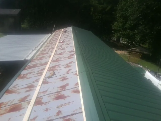 Old rusted panels beside newly installed green metal roofing — Wind Damage Roof Repair by Roofing Brothers in Stratton