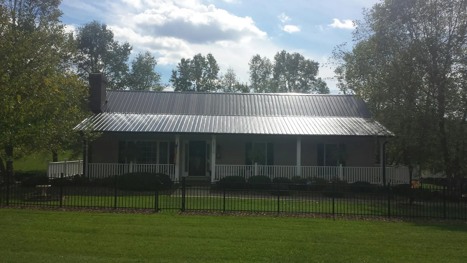 Gray metal roof on a brick ranch with a full width front porch — Gutter Guard Installation work by our crew in Stratton